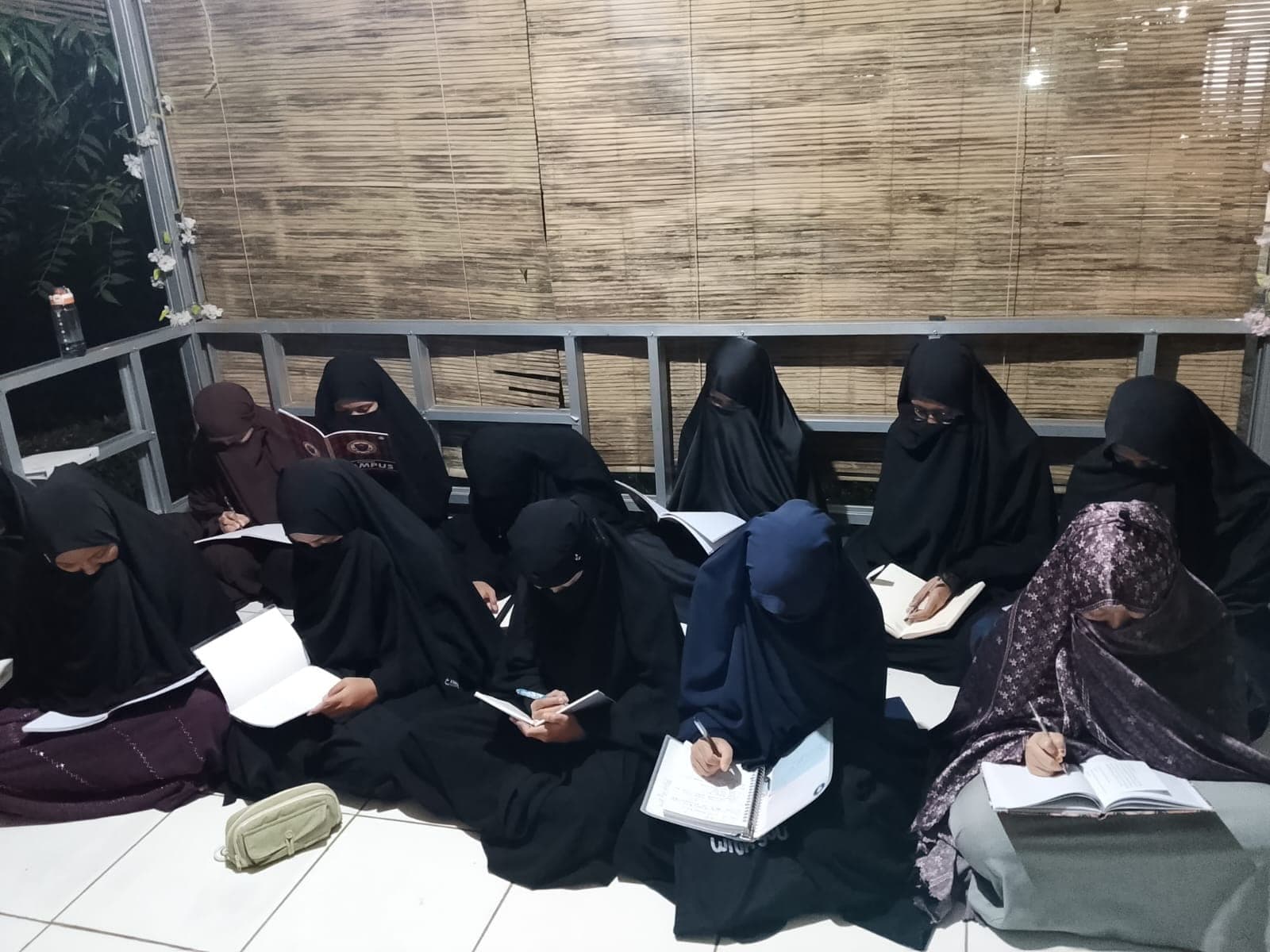 Peserta Imtiaz Putri menyimak dan mencatat sambil duduk lesehan di ruang belajar