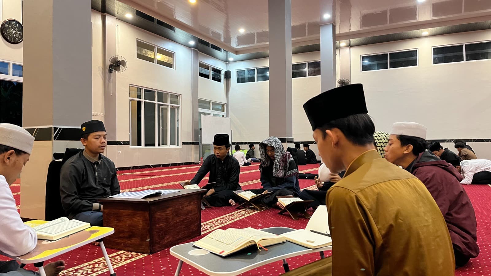 Santri MA Wadi Mubarak bermuraja'ah dengan mushaf di atas meja lipat pada malam hari
