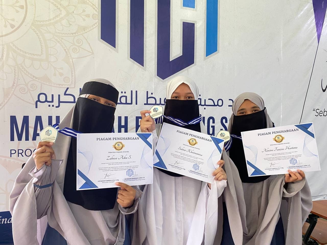 Santriwati Mahabbah Boarding School memegang piagam penghargaan tahfizh dan medali