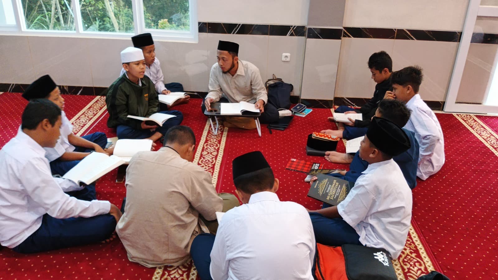 Ustadz membimbing halaqah kajian kitab santri MTs Wadi Mubarak di masjid kampus