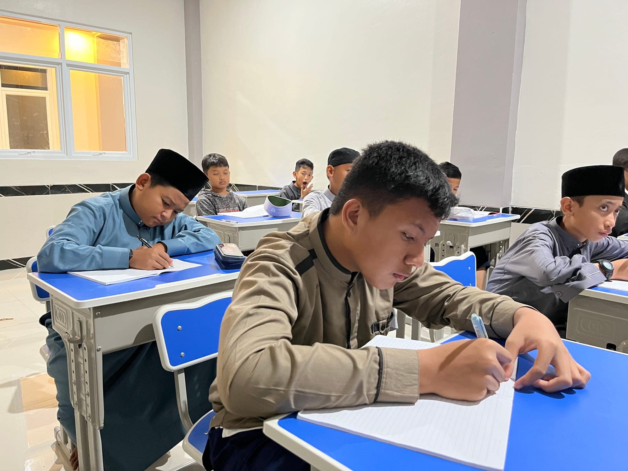 Santri MTs dan MA Wadi Mubarak mencatat pelajaran di buku tulis pada jam belajar malam