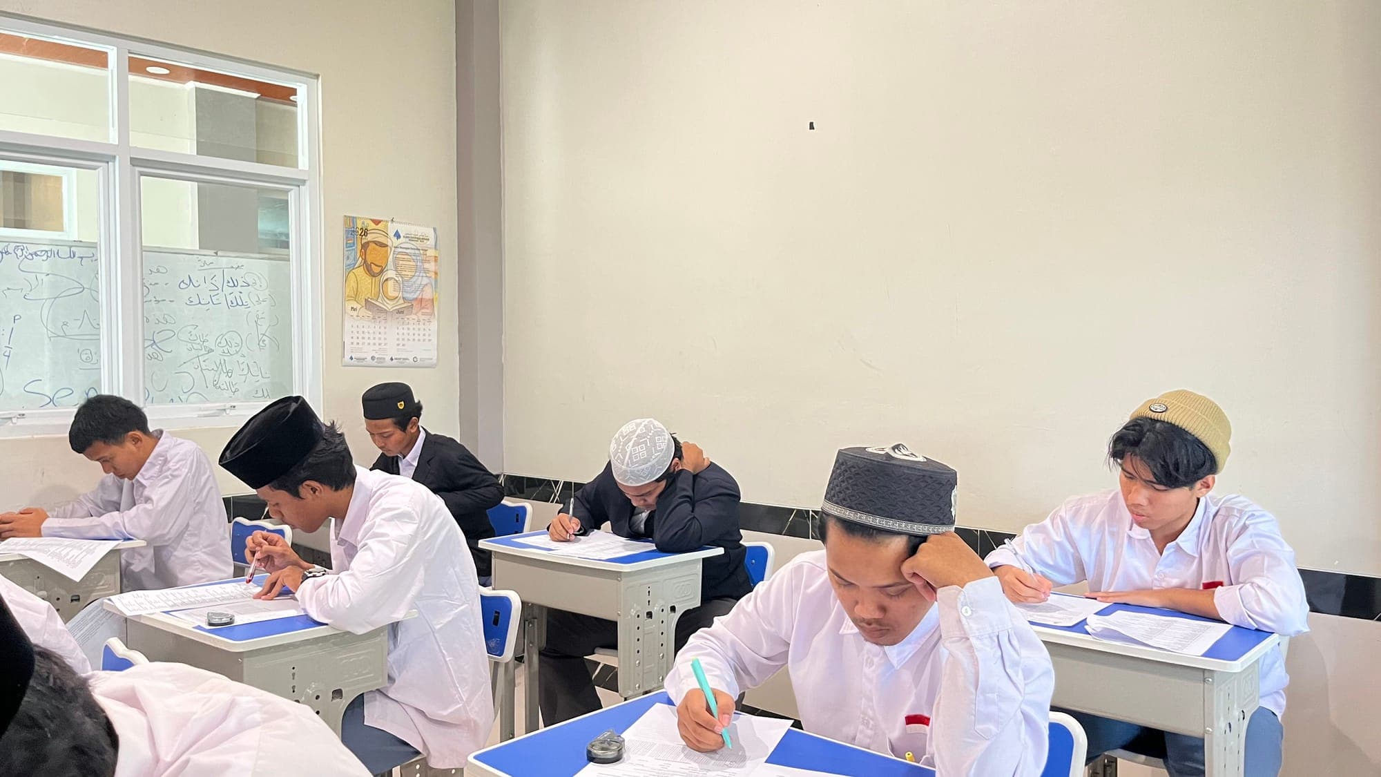 Santri MTs dan MA Wadi Mubarak berkemeja putih mengerjakan soal tertulis di ruang kelas