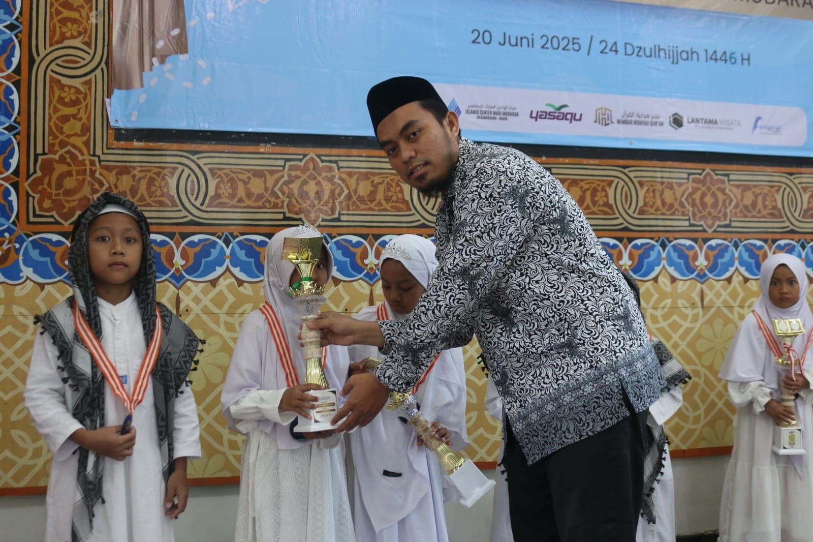 Ustadz menyerahkan piala kepada anak TAUD SAQU pada Penganugerahan Tahfizh 20 Juni 2025