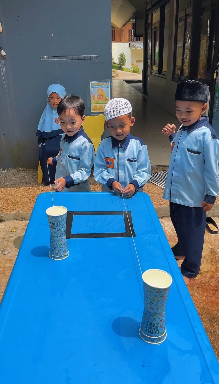 Anak-anak TAUD SAQU bermain menyusun gelas di atas meja biru